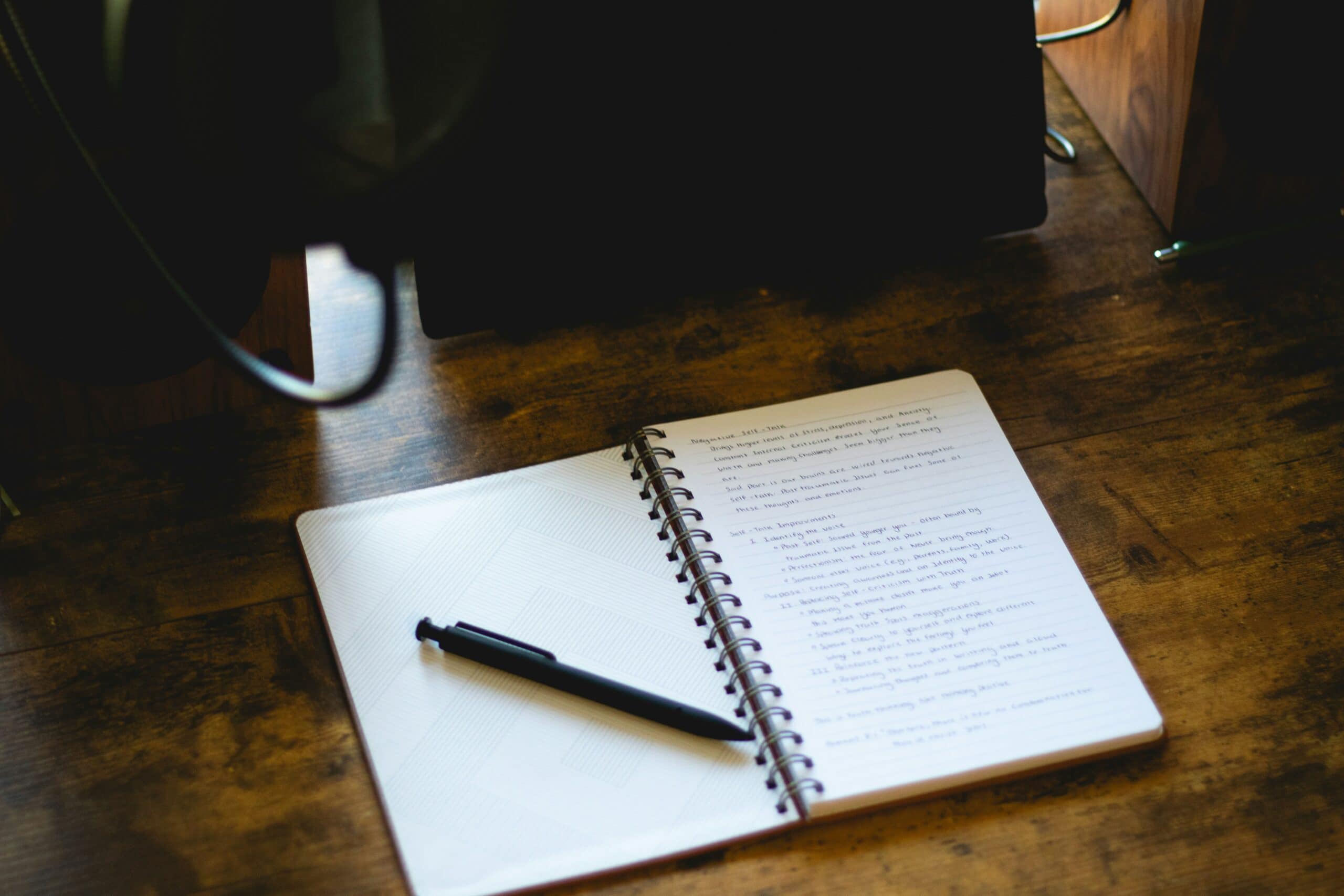 Handwritten notebook open on a table, pausing to reflect before acting
